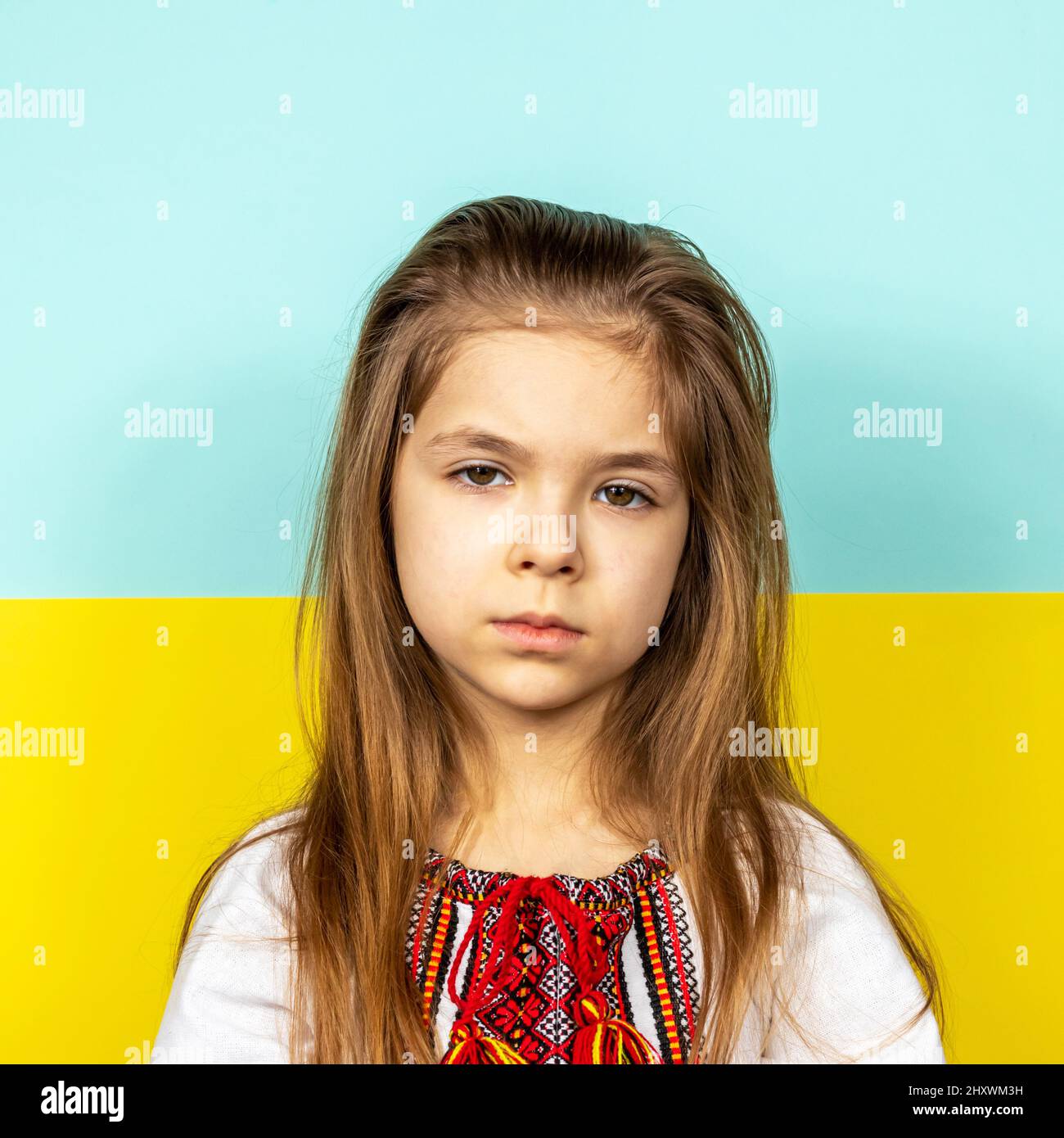 Sad girl in the national Ukrainian vyshyvanka on the background of the Ukrainian flag. Stop the war in Ukraine. The concept of peace in Ukraine Stock Photo