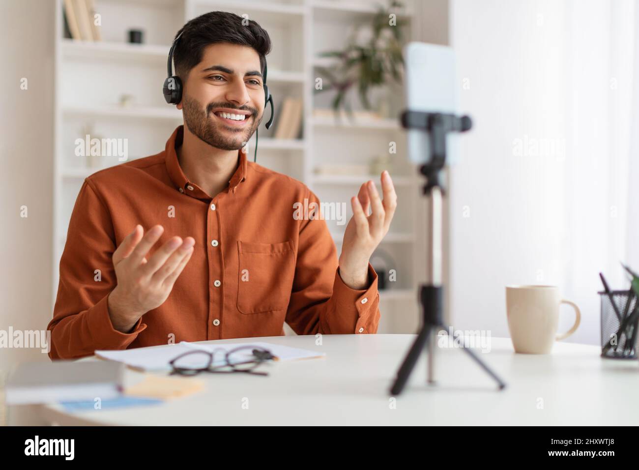 Arab man having videocall using cellphone on tripod Stock Photo