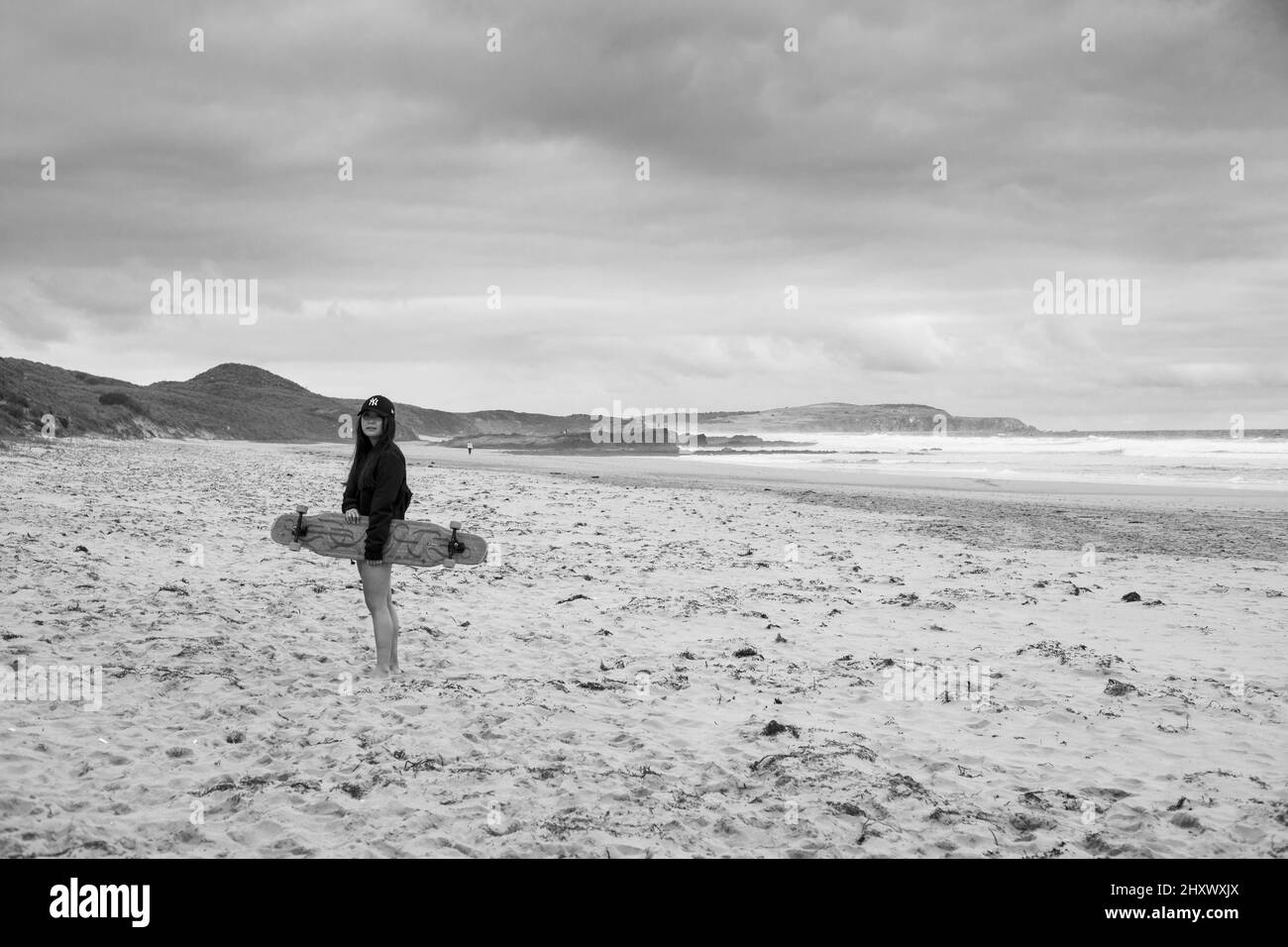 Black and white shot of a surfer walking a long a beach Stock Photo - Alamy