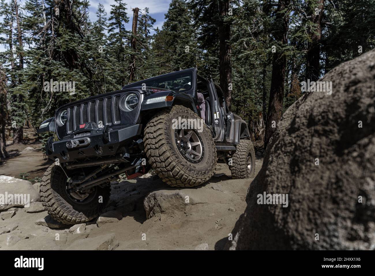 A Jeep Wrangler Rubicon offroading on a rocky ground against a light