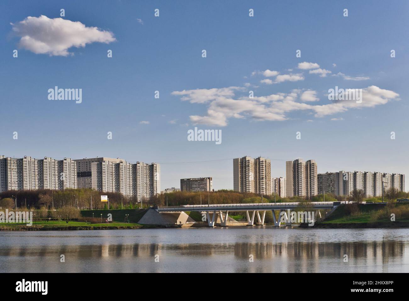 Beautiful calm urban cityscape at summer day. View on lake, park, road