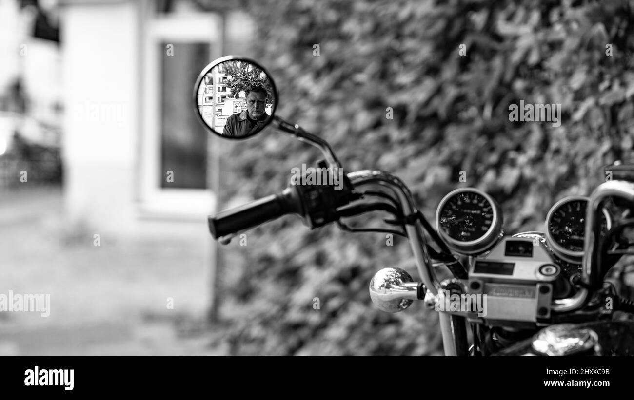 Grayscale of a man reflecting in the side mirror of a bicycle Stock Photo