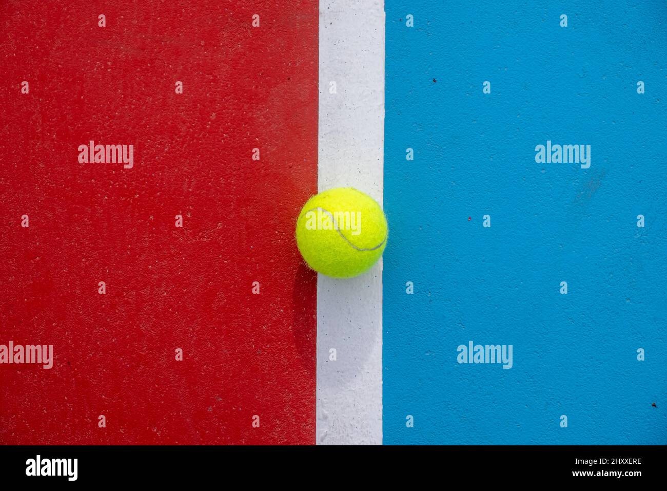 Yellow tennis ball placed on a wall colored with red, blue and
