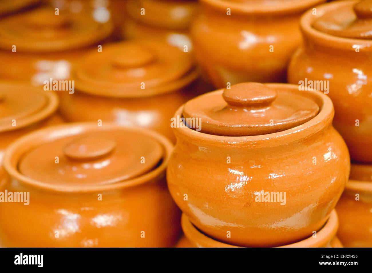 Lot of same ceramic brown terracotta clay pots with lids closeup Stock