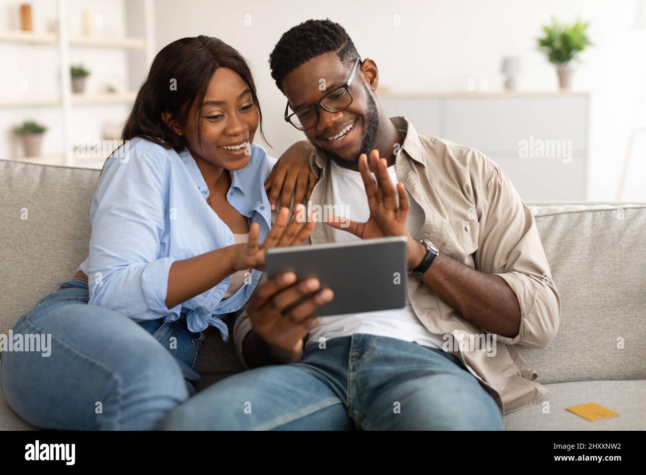 Black couple having videocall using tablet waving hands Stock Photo