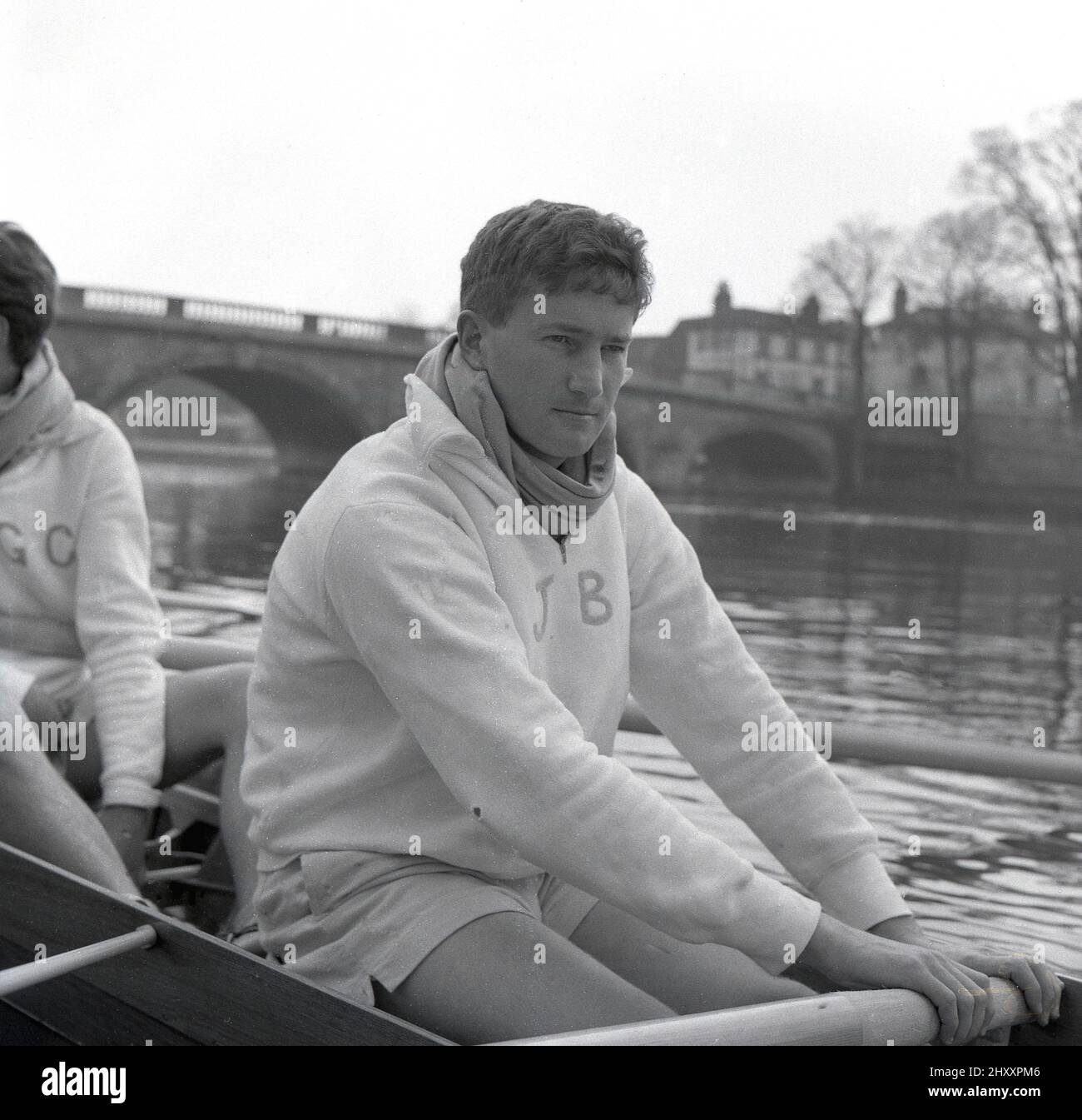 1960, historical, sitting in a rowing boat on the water, crew member of the Cambridge University Boat team, J. Beveridge of Jesus college, with JB embrodied on his cotton tracksuit top. This was the third appearance of John Beveridge in the race and he was the Cambridge president this year. The famous university rowing race, The Oxford & Cambridge Boat Race, first took place 1829 and is a yearly event on the River Thames on the championship course between Putney and Barnes in South West London. Stock Photo