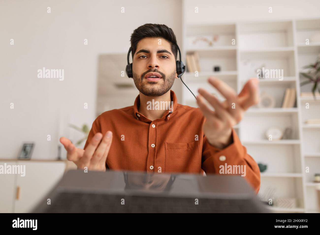 Arab man using laptop wearing headset sitting at desk Stock Photo