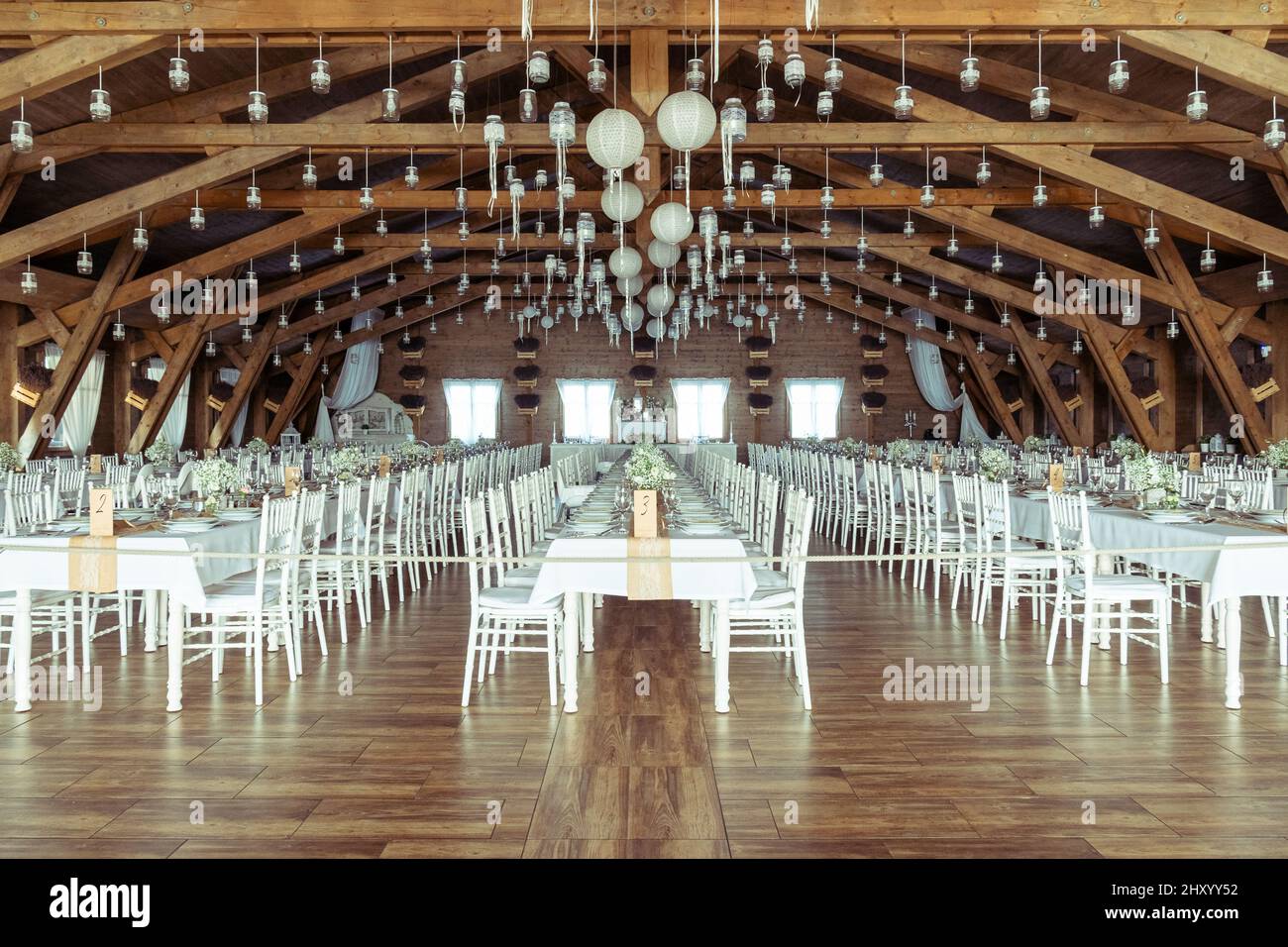 View of a banquet or wedding hall with long white tables and chairs and ...