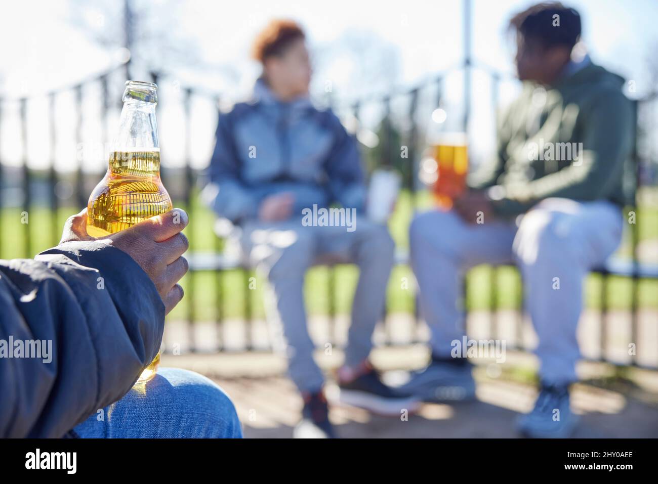 Close Up Of Underage Teenagers Drinking Alcohol In Park Stock Photo