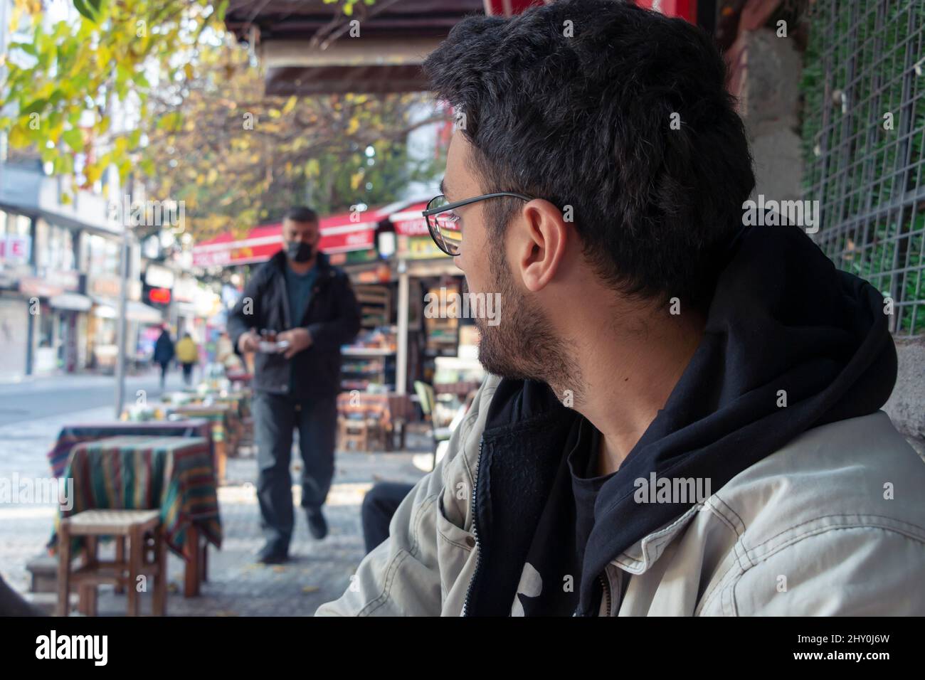 A man sitting in a cafe. He ordered a tea. Waiter is serving tea. Stock Photo