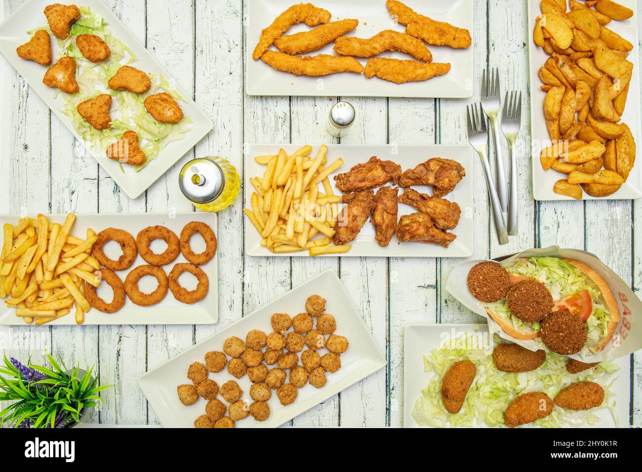 Set of battered fried chicken dishes, nuggets, potato wedges, falafel sandwich, croquettes, fried chicken strips, wings with potatoes, onion rings and Stock Photo