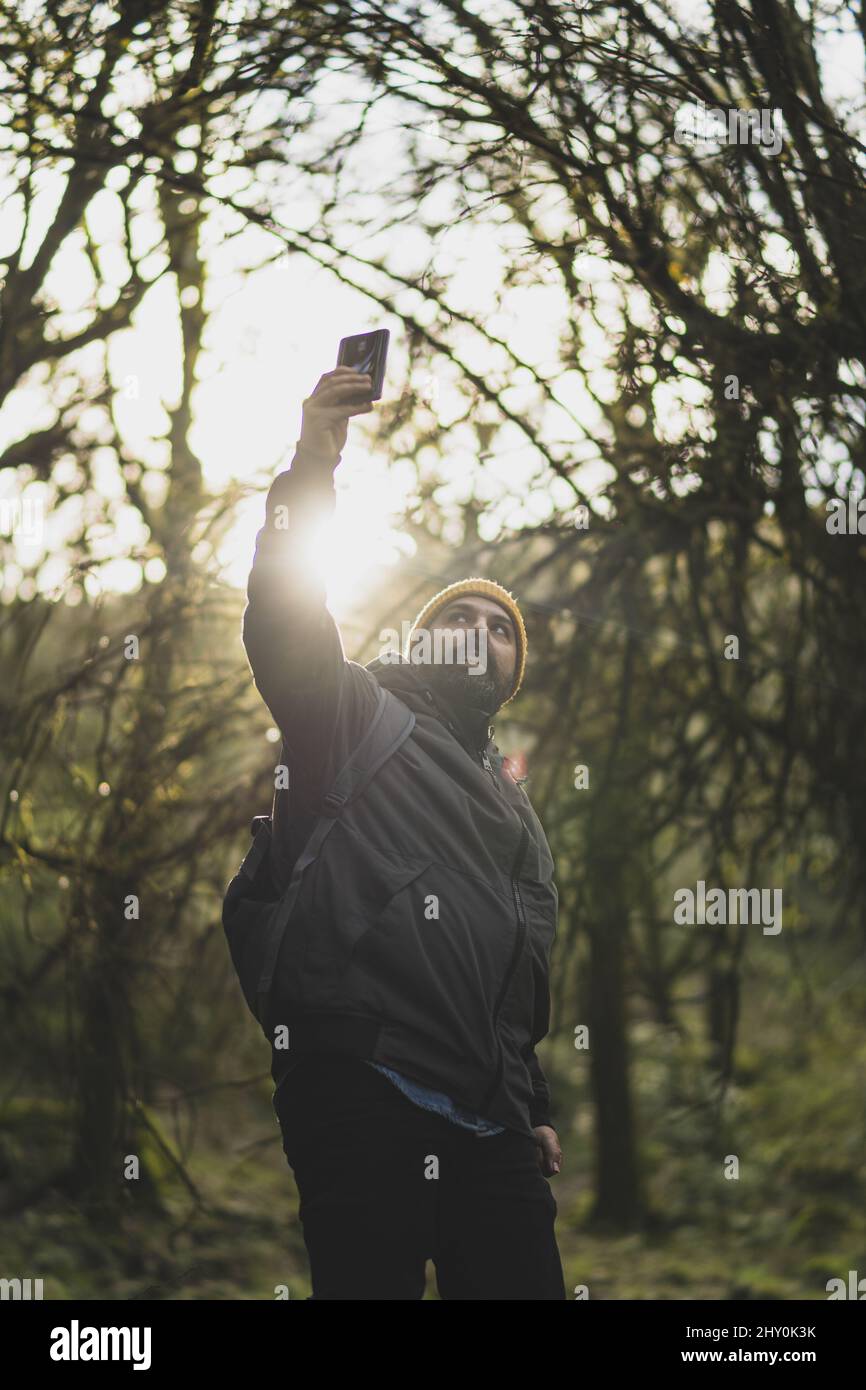 Young male taking a selfie in a lush forest during the hike with a ...