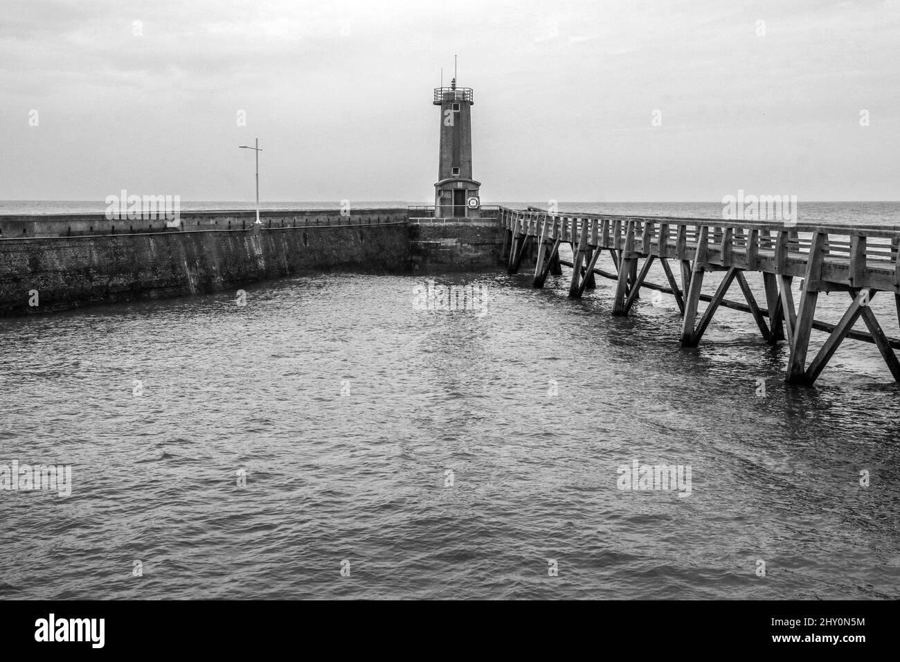 The wooden pedestrian bridges over the sea water leading to the lighthouses in the harbor of the city of Fécamp in Normandy in France. Stock Photo