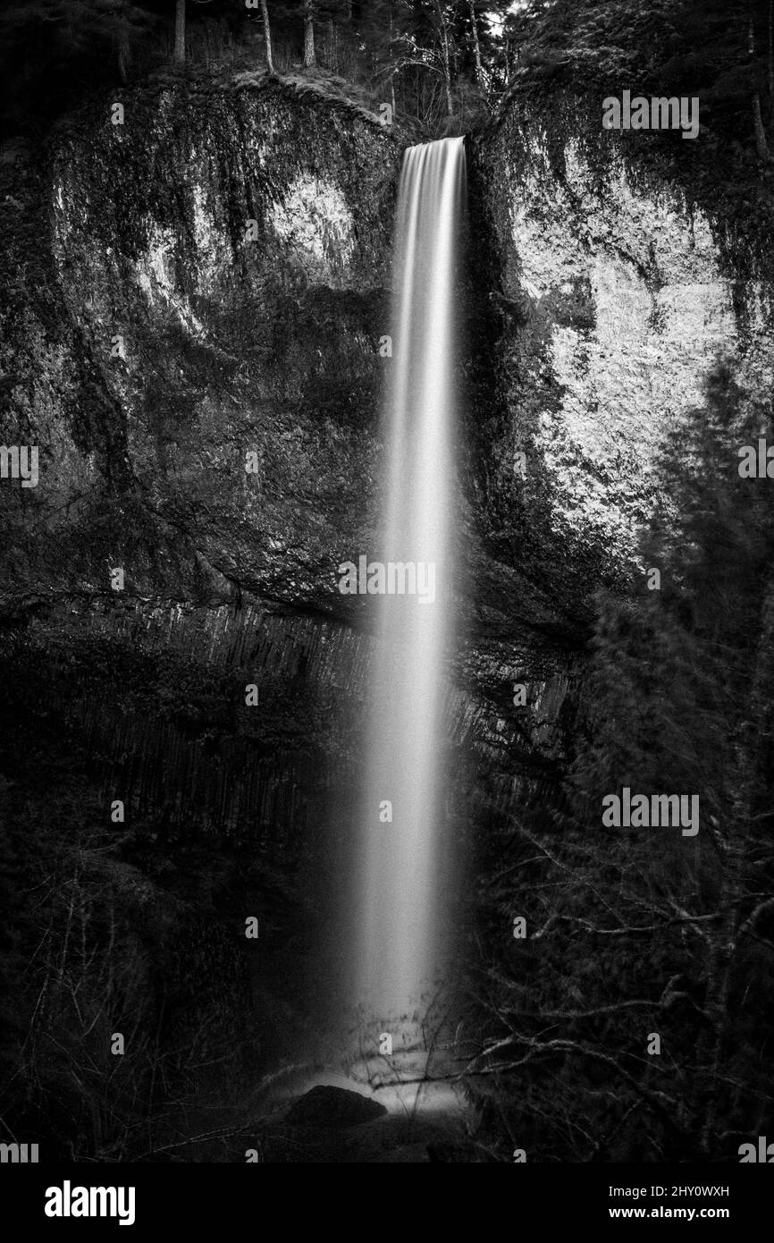 Vertical shot of a waterfall flowing down the rocks covered with moss ...