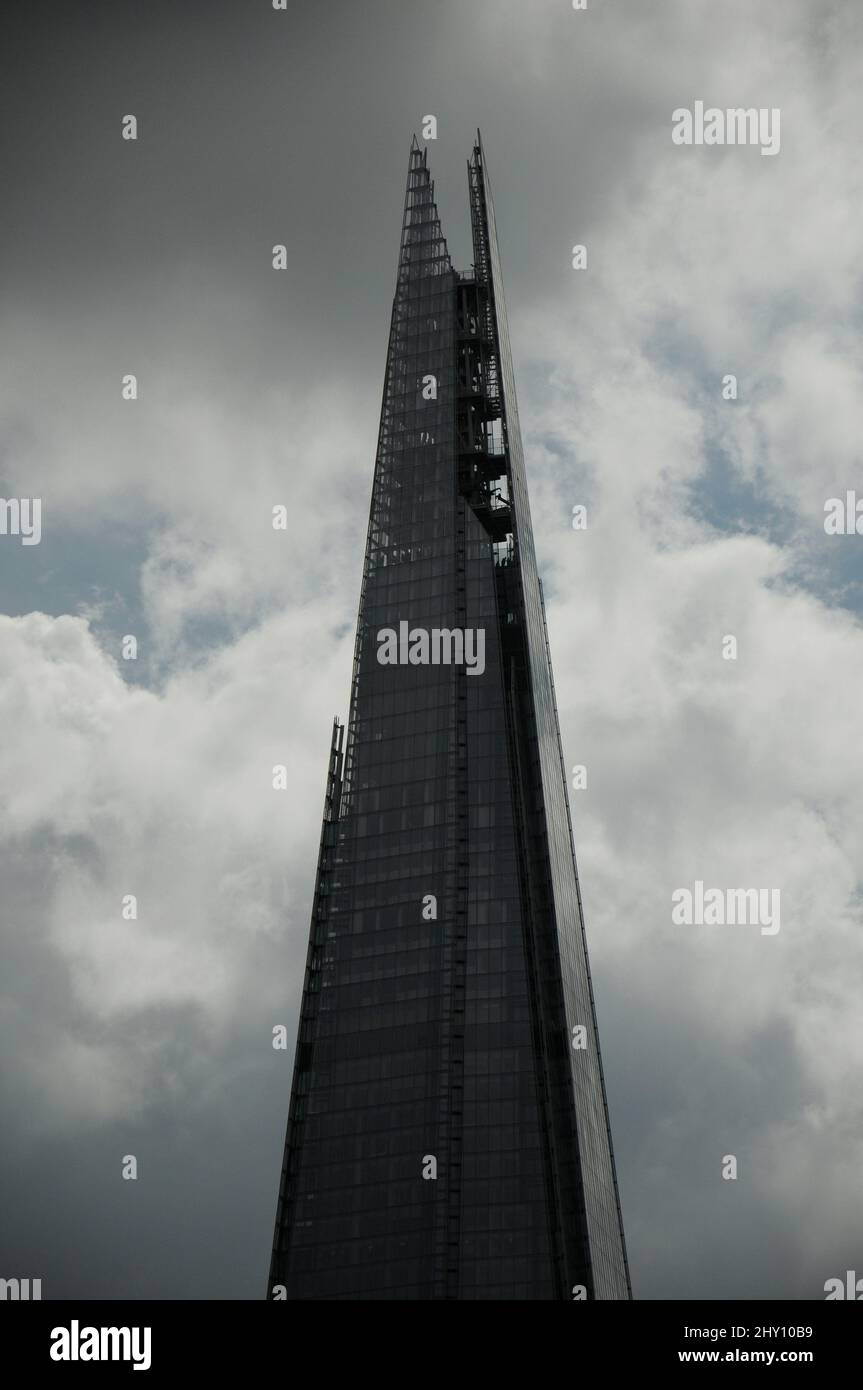 Vertical shot of the top of the Shard against the cloudy sky. London ...