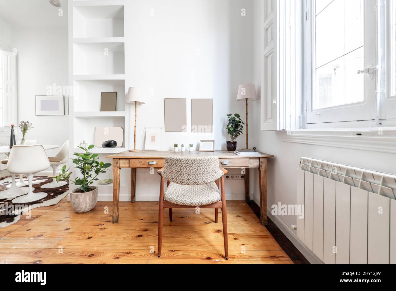 Antique wooden desk with upholstered chair and plaster bookcase next to a white wooden window Stock Photo