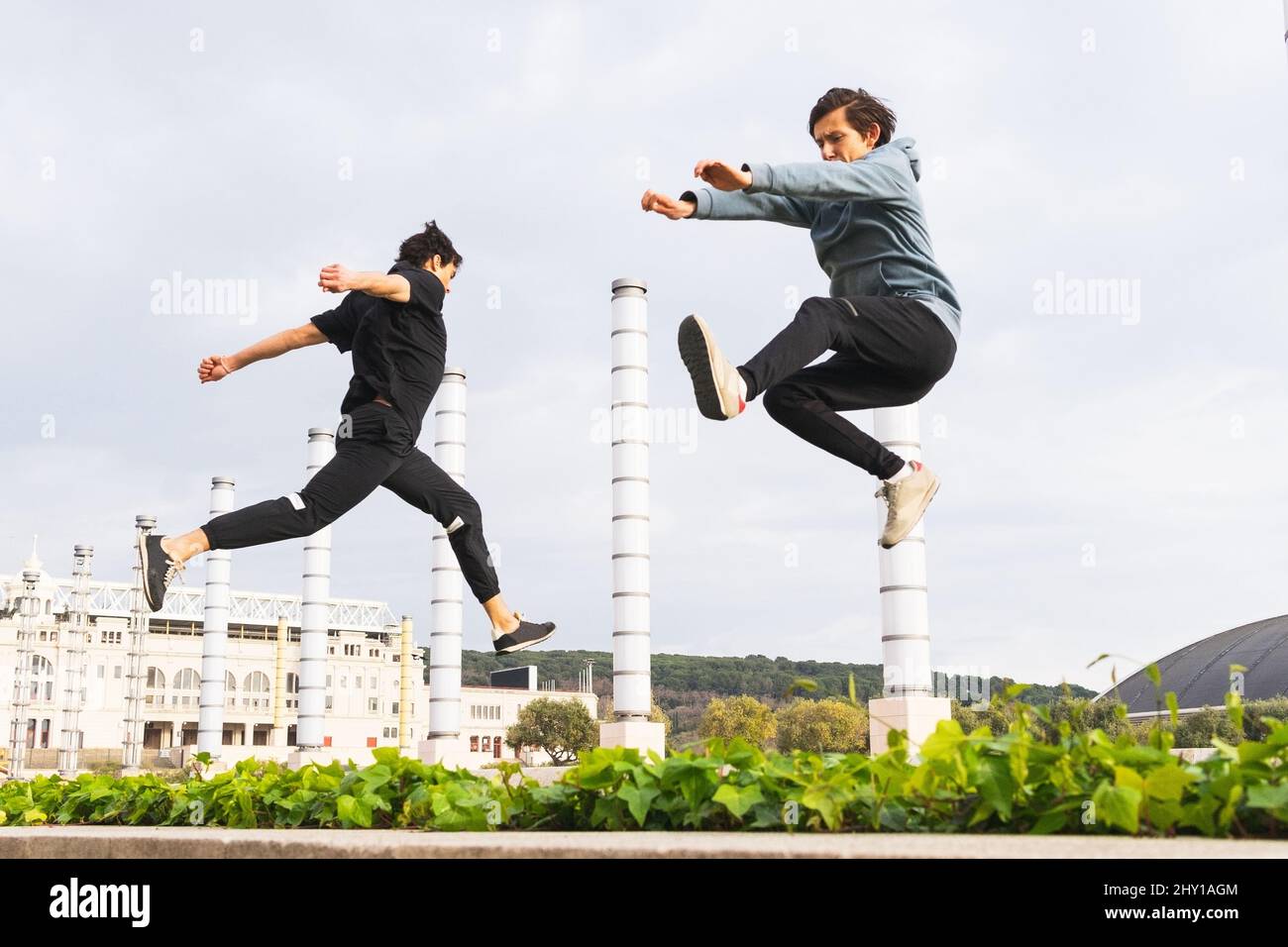 Side view of full body strong parkour athletes in sportswear doing jump