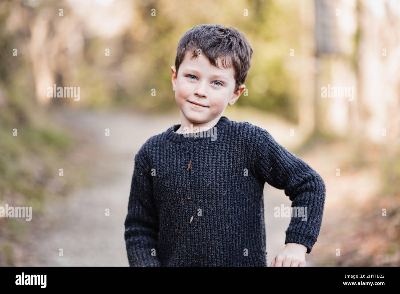 Cute little boy with blue eyes wearing warm sweater winking and looking at camera Stock Photo