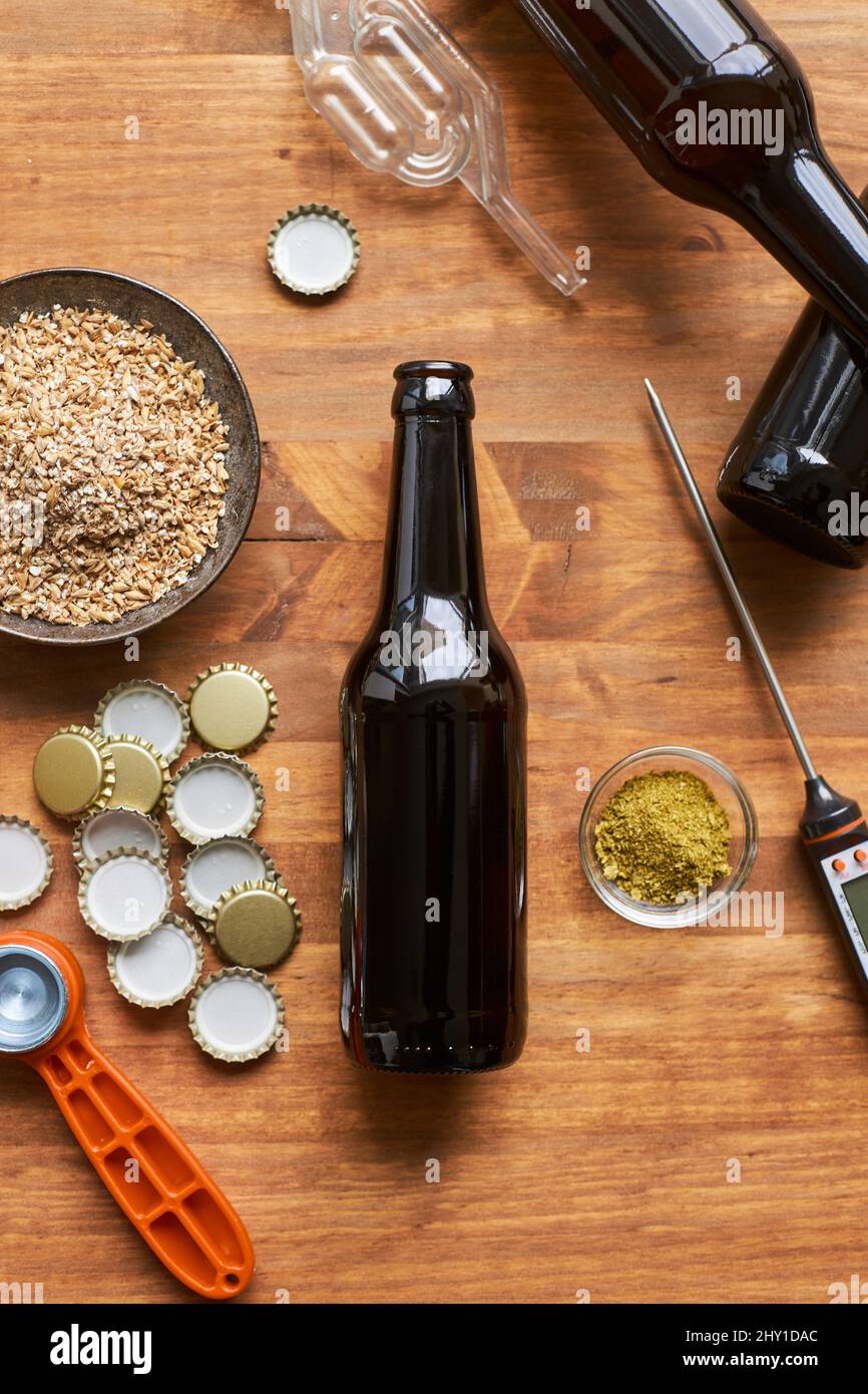Top view of glass bottle near bowl of barley grains and metal caps on