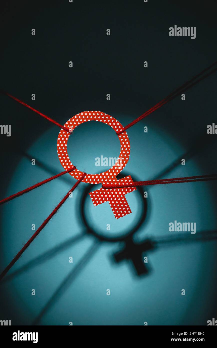 From above of red polka dot Venus symbol tied with ropes representing gender inequality in room with shadow and dim illumination Stock Photo