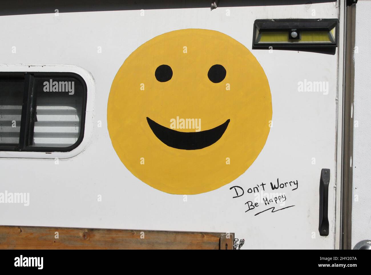 Smiley emoji face and Don't worry, Be Happy text on the old trailer in