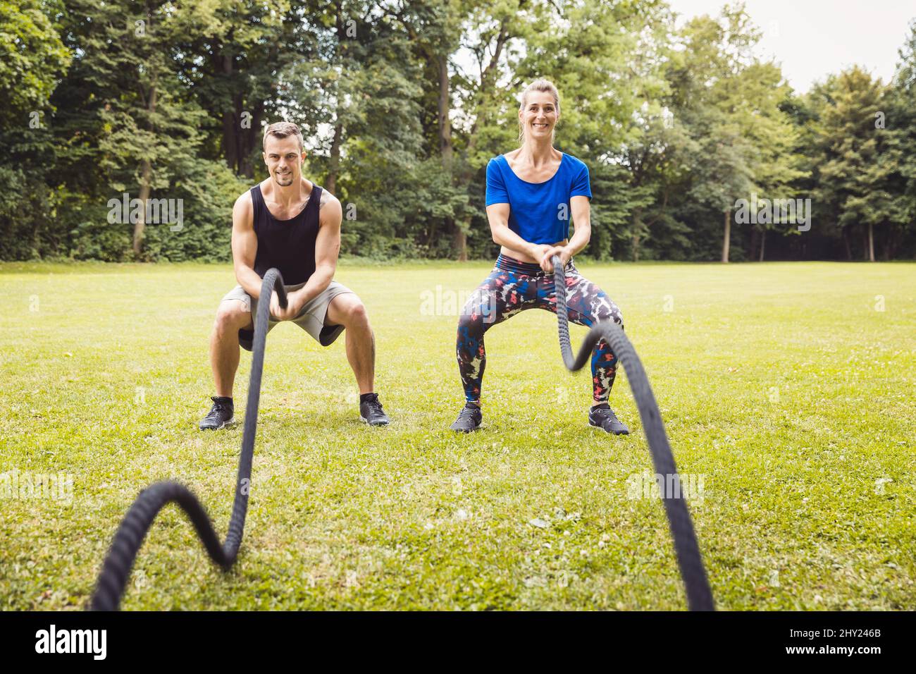 Young man and woman exercising using battle rope Stock Photo