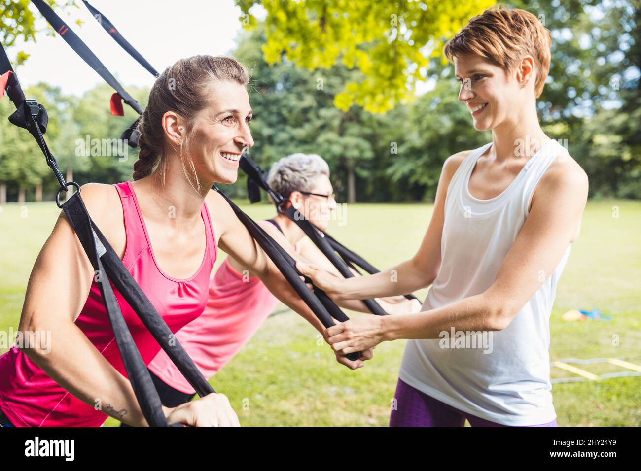 Smiling young woman exercises using suspension training Stock Photo