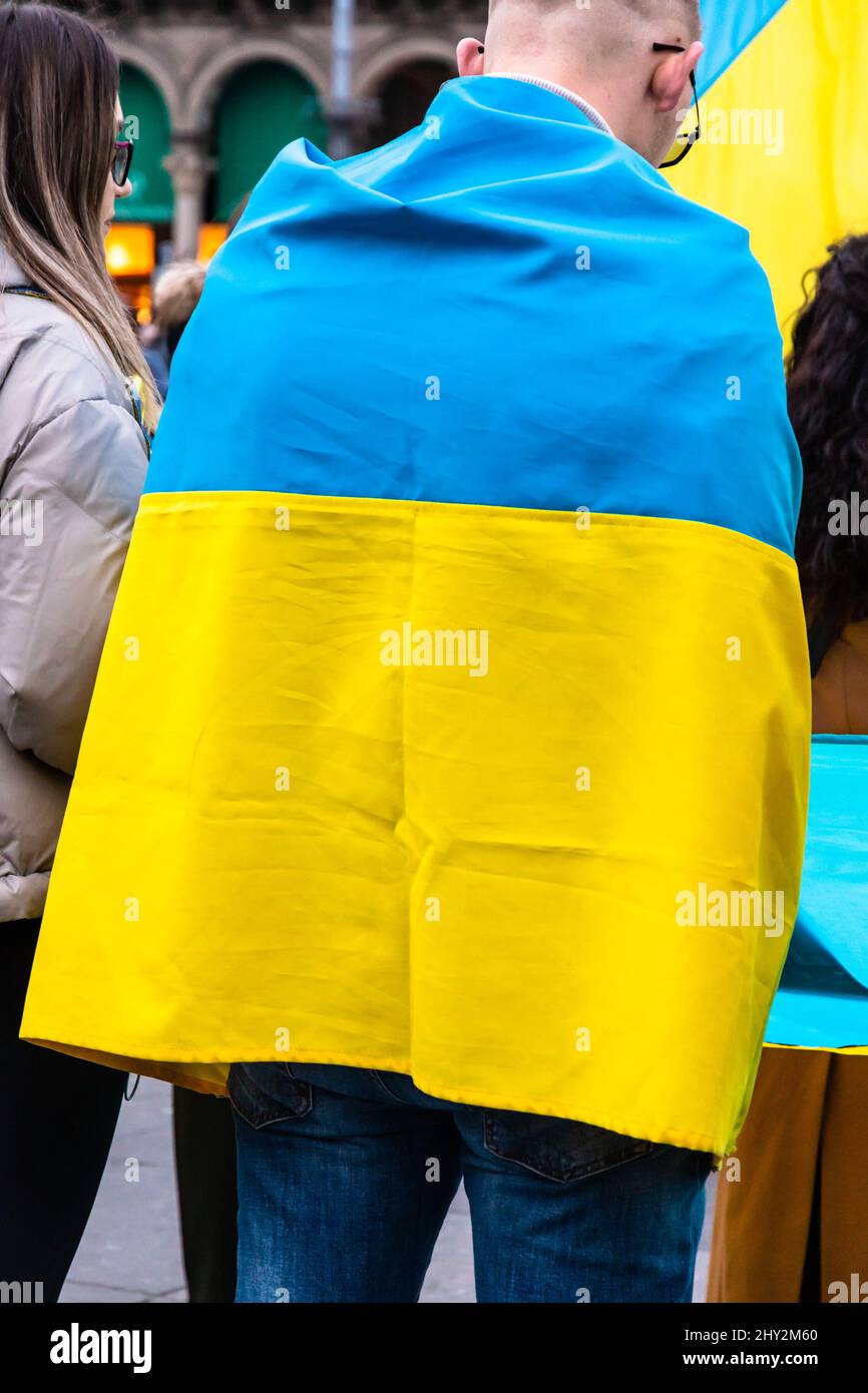 Young man wrapped in the Ukrainian flag in a protest against Russia invasion Stock Photo