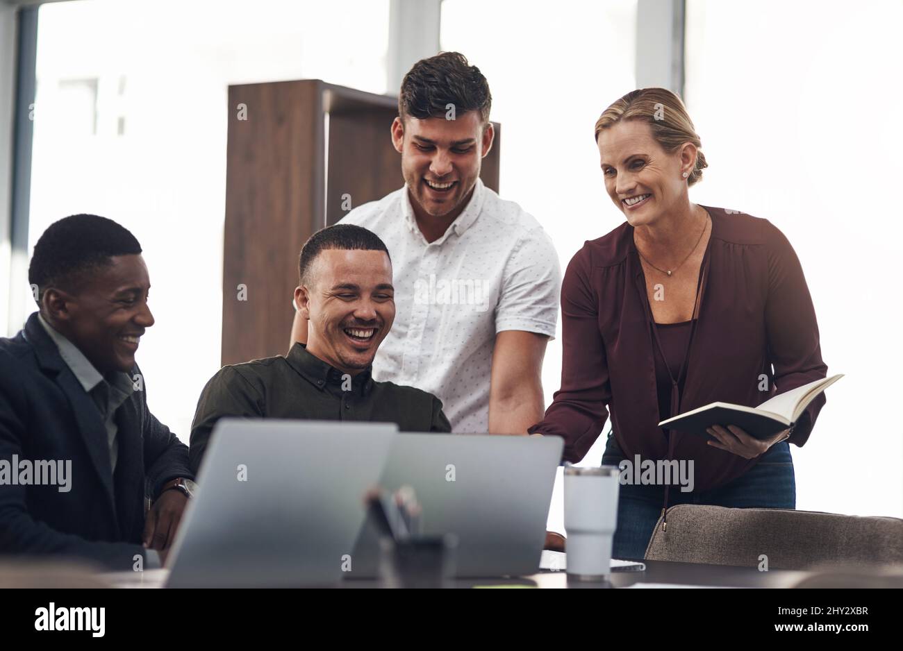 Seeing their plan all come together. Shot of a group of businesspeople working together on a laptop in an office. Stock Photo