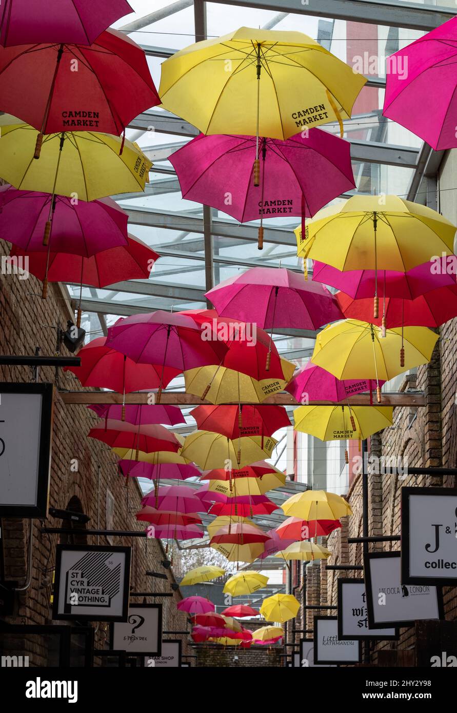 Colourful yellow and red umbrellas hanging above an alleyway full of boutique stores in Camden