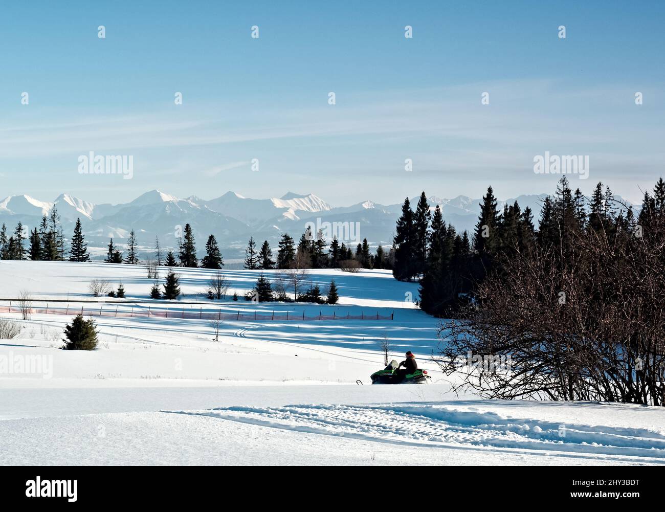 Polish Tatra Mountains, snowmobile and winter recreation, mountain peaks and a wall of mountain trees Stock Photo