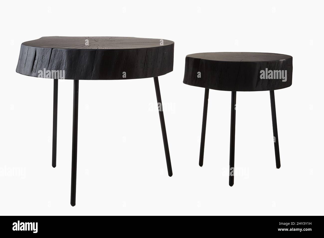 Shot of two black three legged stools made of wood trunk and steel isolated on a white background Stock Photo