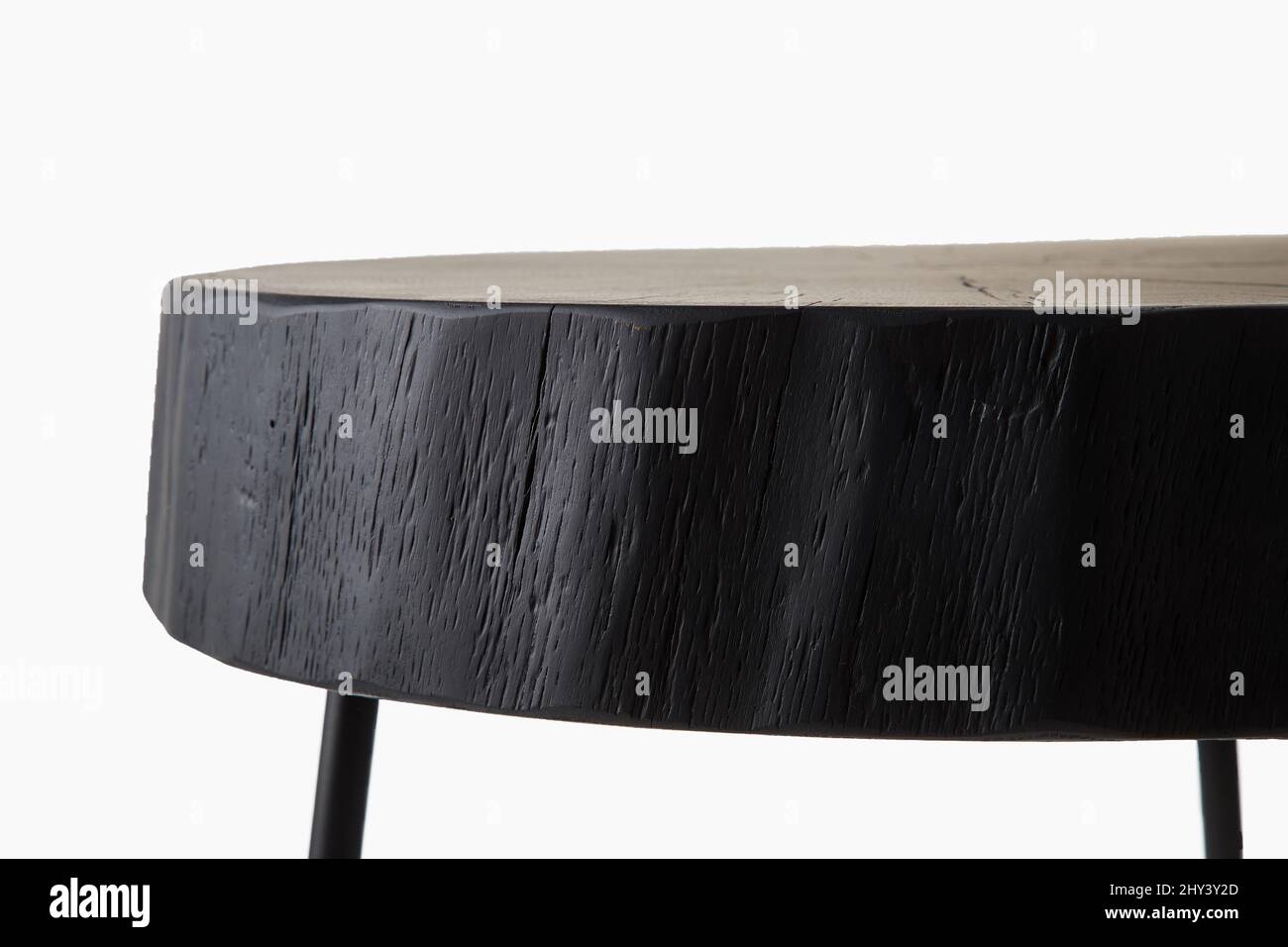 Close-up shot of black three legged stool made of wood trunk and steel isolated on white background Stock Photo
