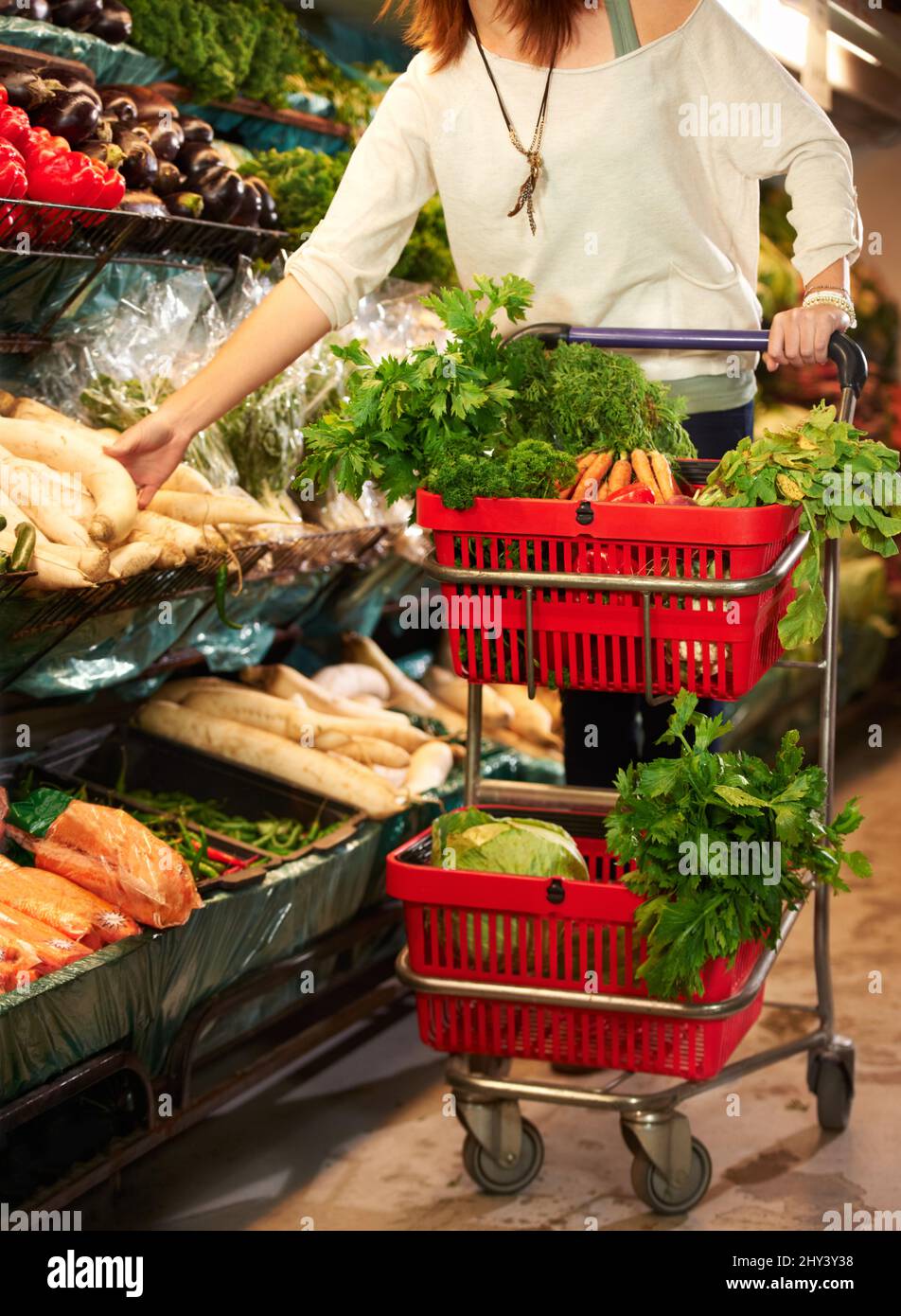Stocking up on fresh veggies. Cropped image of a woman pushing a ...