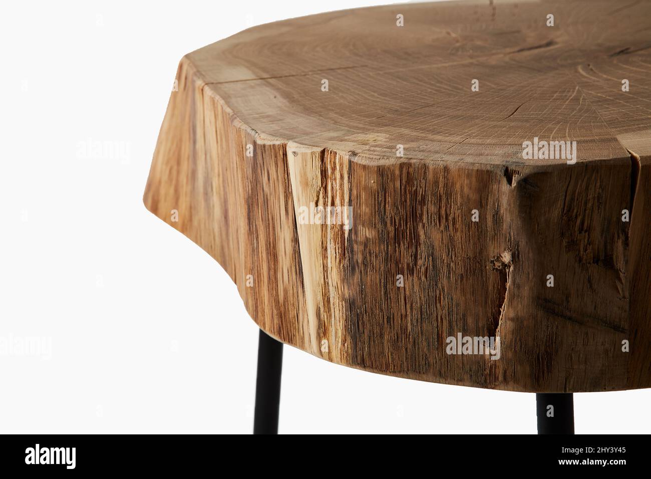 Close-up shot of a three legged stool made of wood trunk and steel isolated on a white background Stock Photo