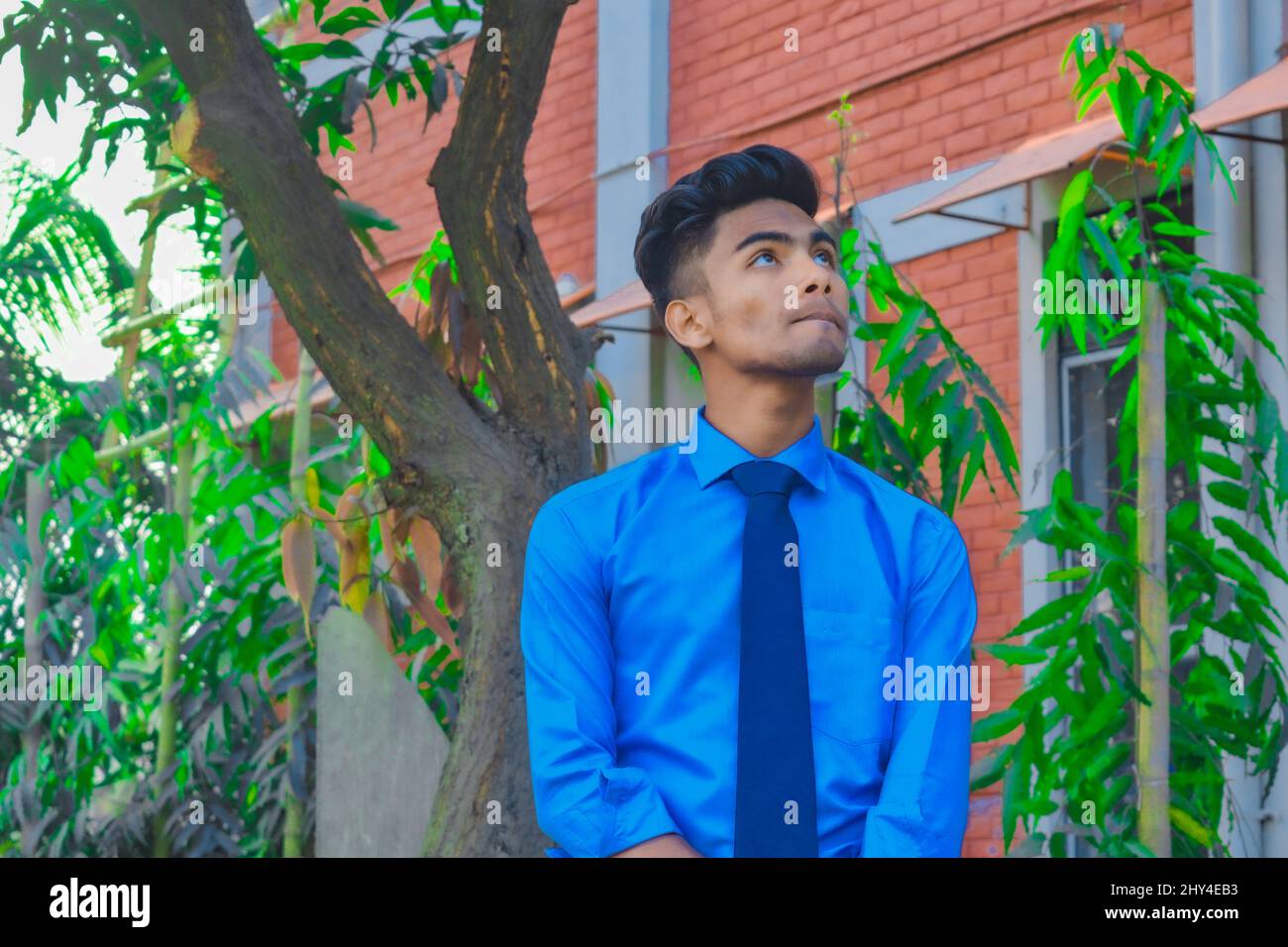 Young handsome man wearing a blue tie and shirt in a garden Stock Photo