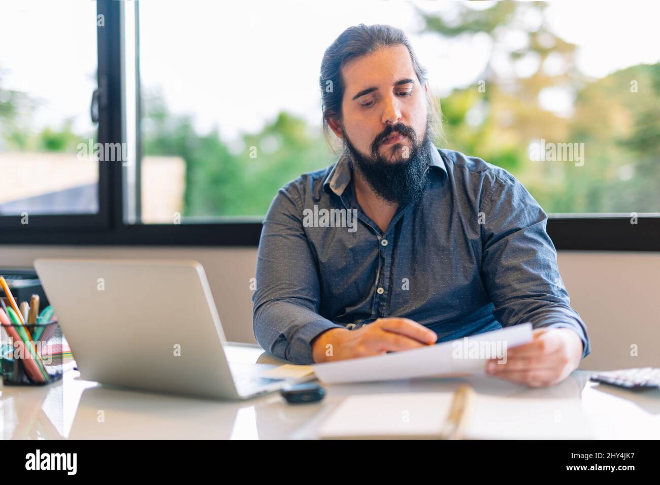 Young entrepreneur consulting documents while working at home Stock Photo