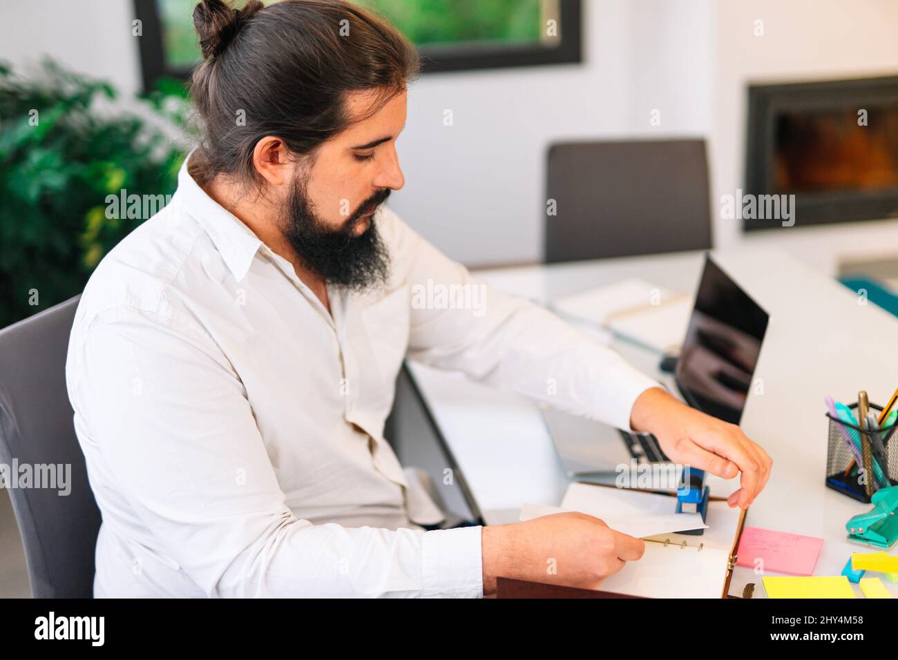 Young entrepreneur stapling papers while working at home.  Stock Photo