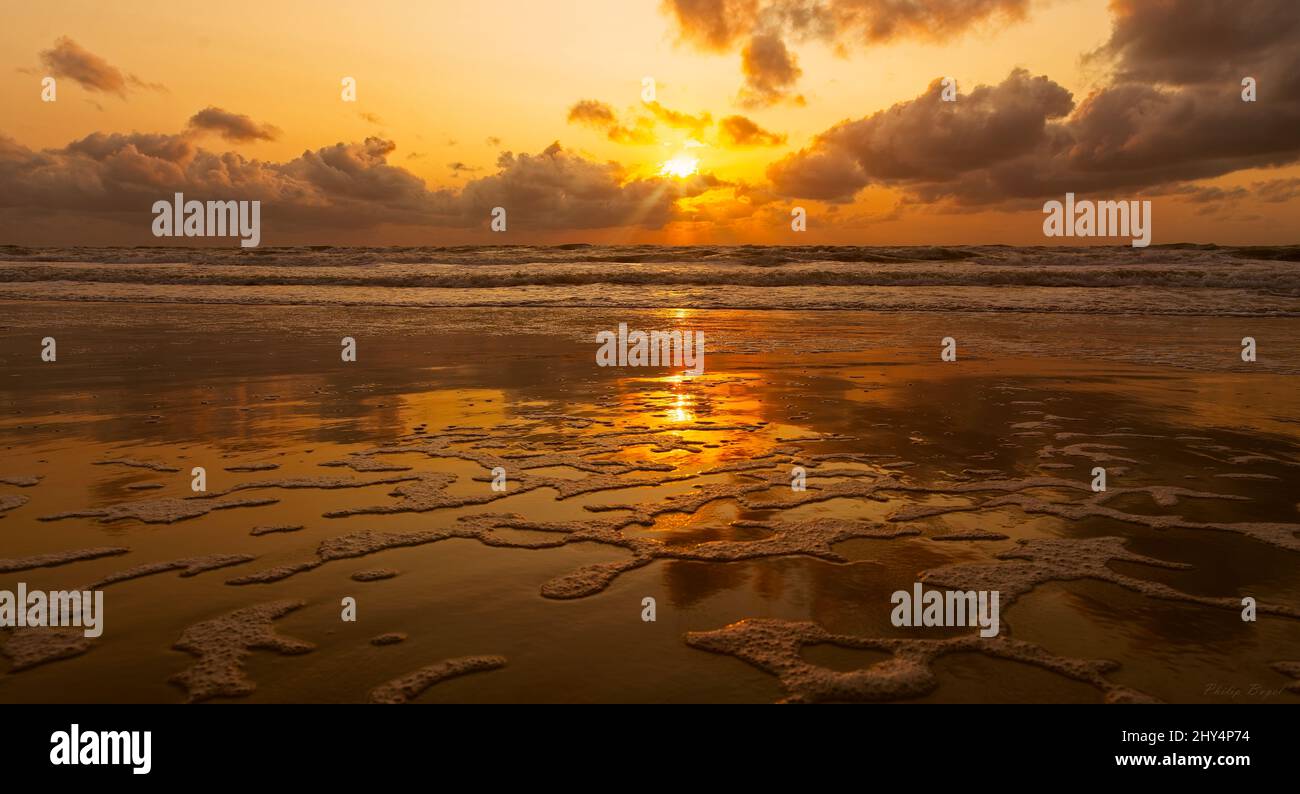 Beautiful view of a sunset over the beach with huge waves with clouds ...