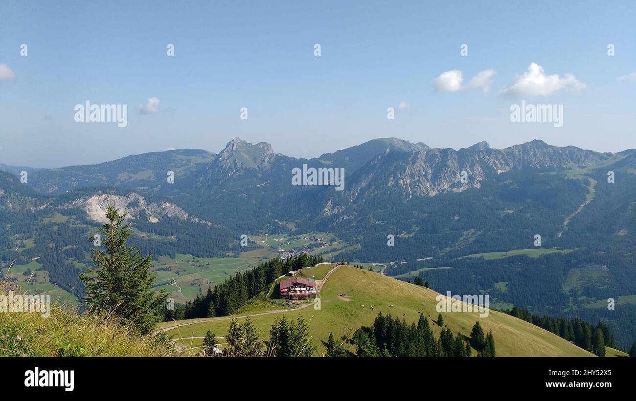 Wooden house in a green field surrounded with mountains Stock Photo - Alamy