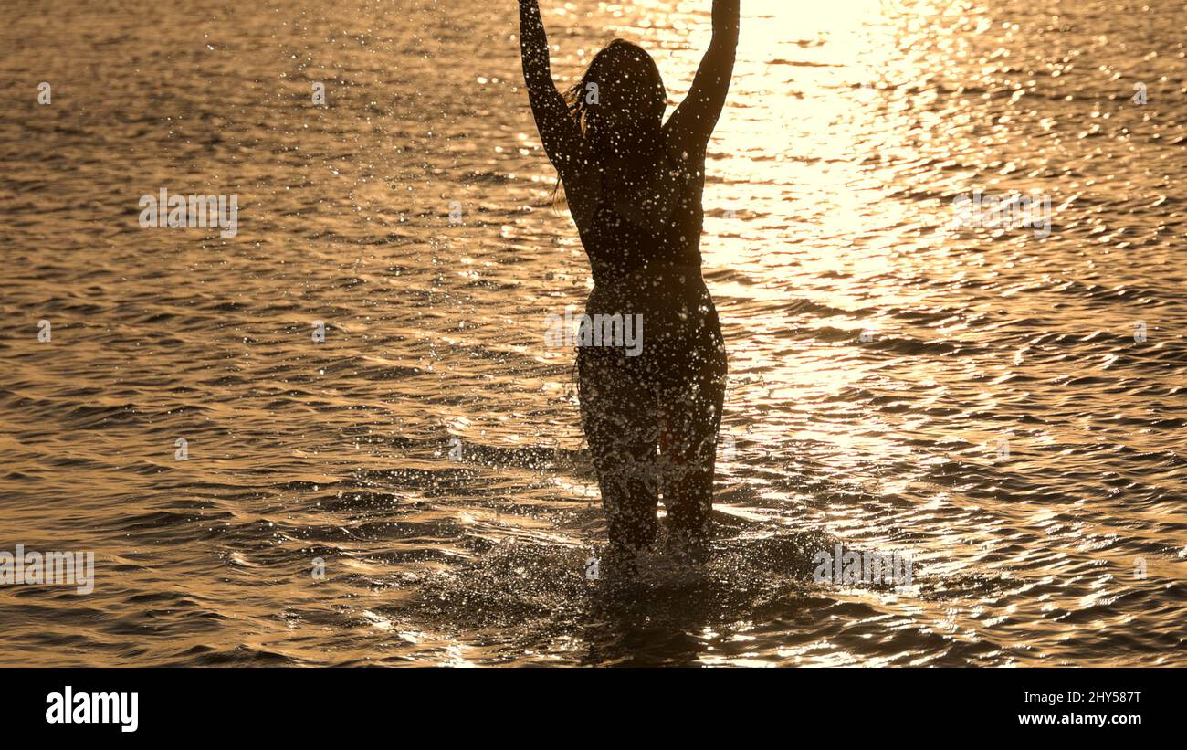 Silhouette shot of a beautiful woman on sunset shot against the golden ...
