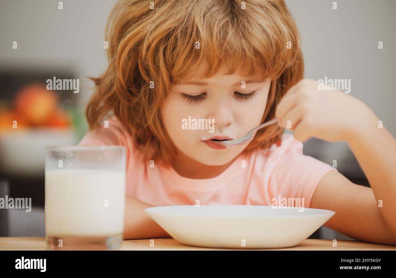 Caucasian toddler child boy eating healthy soup in the kitchen. Stock Photo