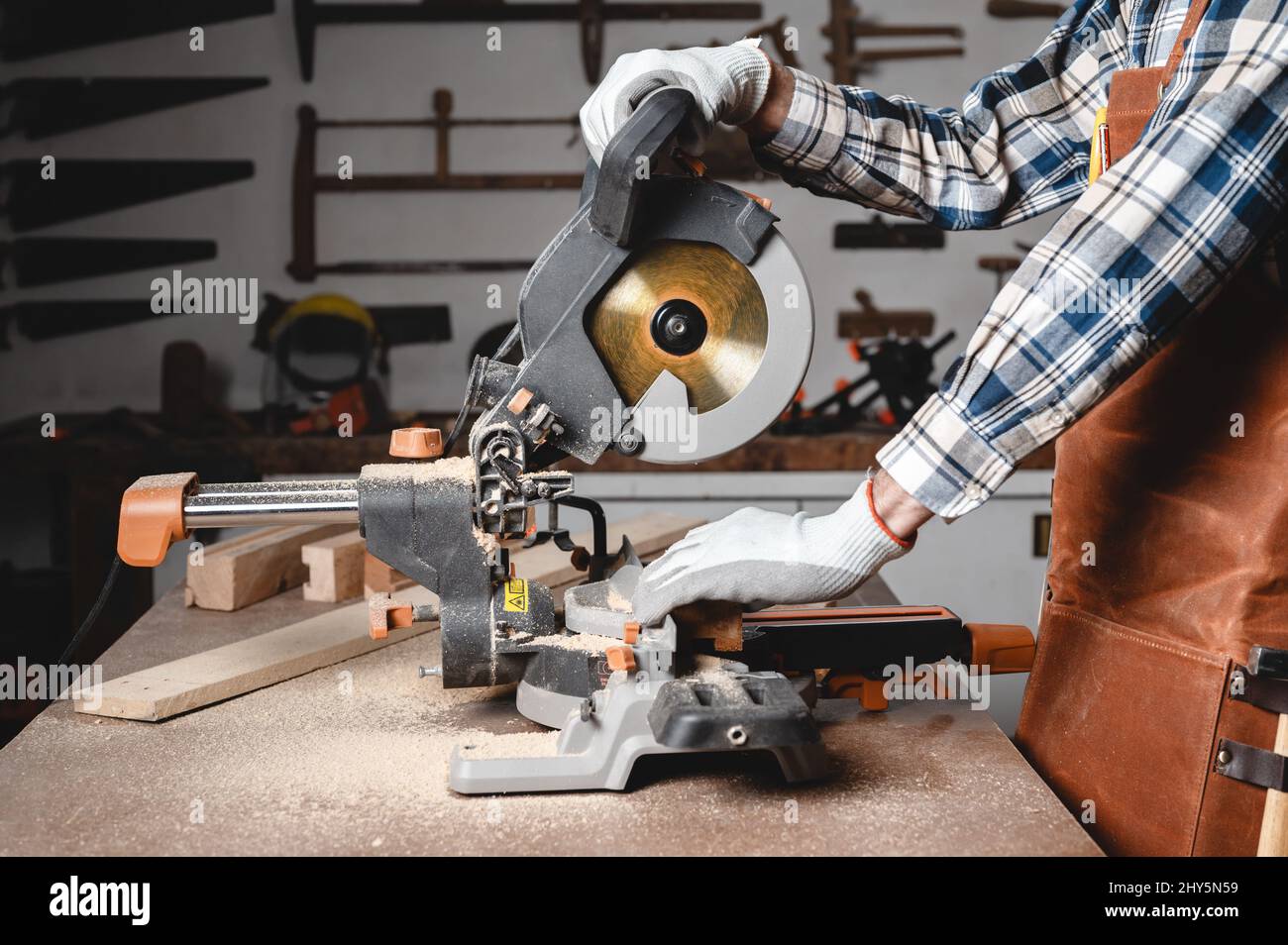 Carpenter using an electric circular saw, cutting piece of wood. High quality photo. Stock Photo