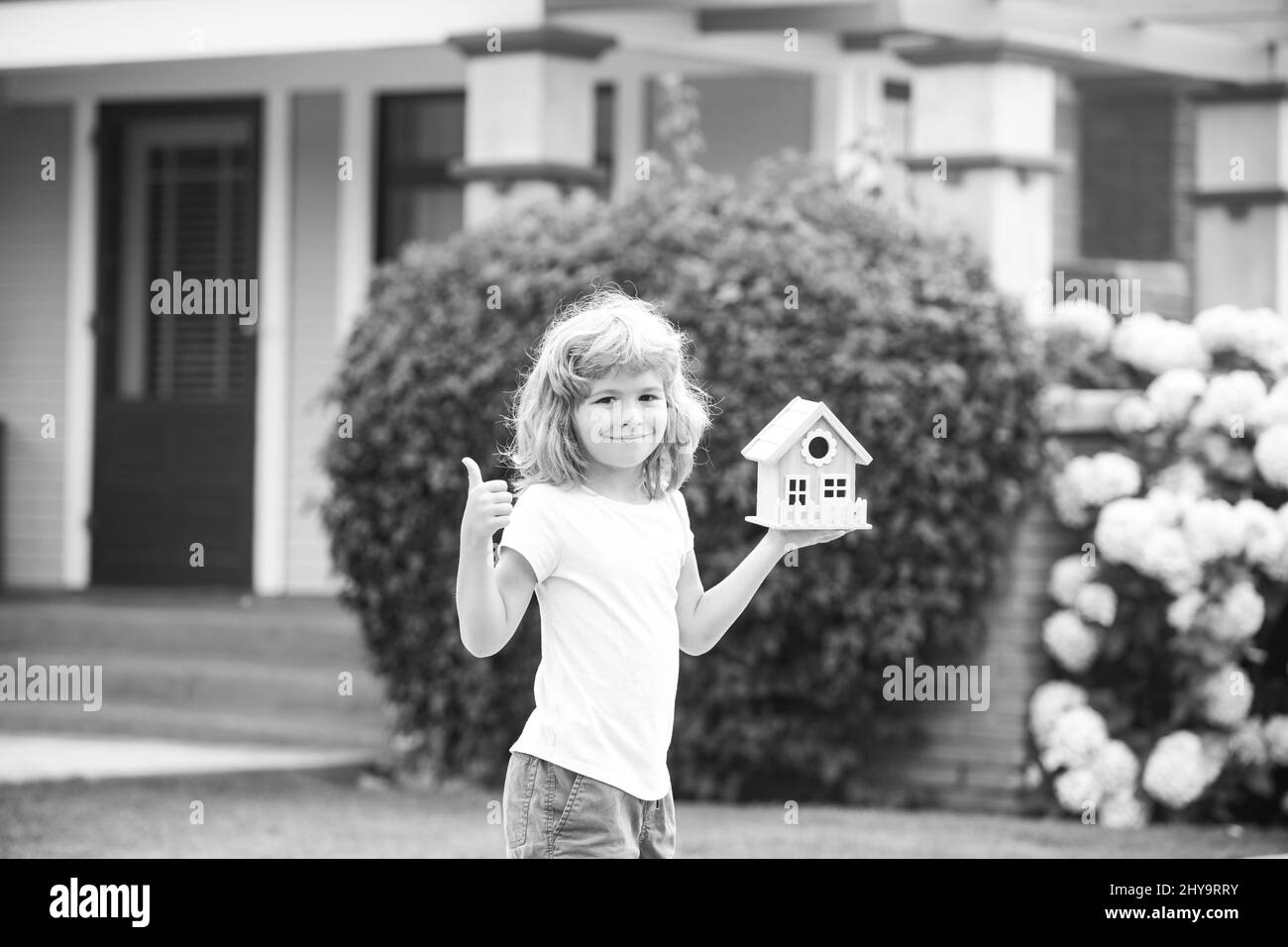 Kid dreaming of new home. Happy boy holding dream house in their hands, real estate and home insurance concept. Mortgage, house insurance, future Stock Photo