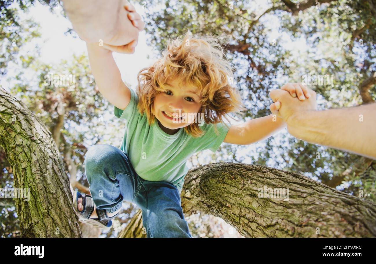 Father helping son. Fathers hand and helping son to climb tree. Child protection. Stock Photo