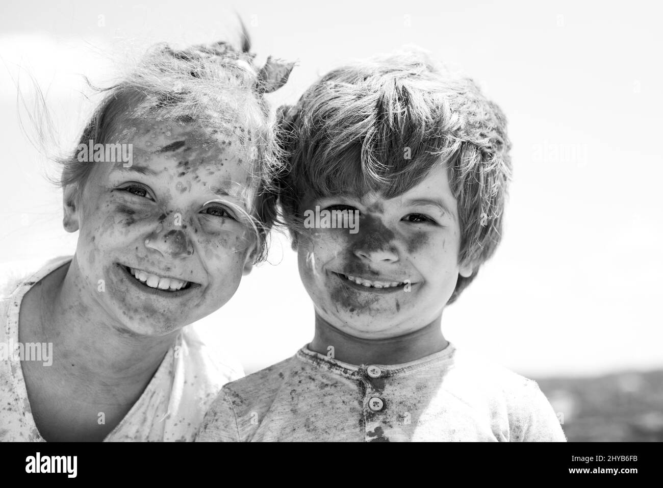 Smiling little kids portrait. Painted faces of funny kids. Children holi festival of colors. Little boy and girl plays with colors. Stock Photo