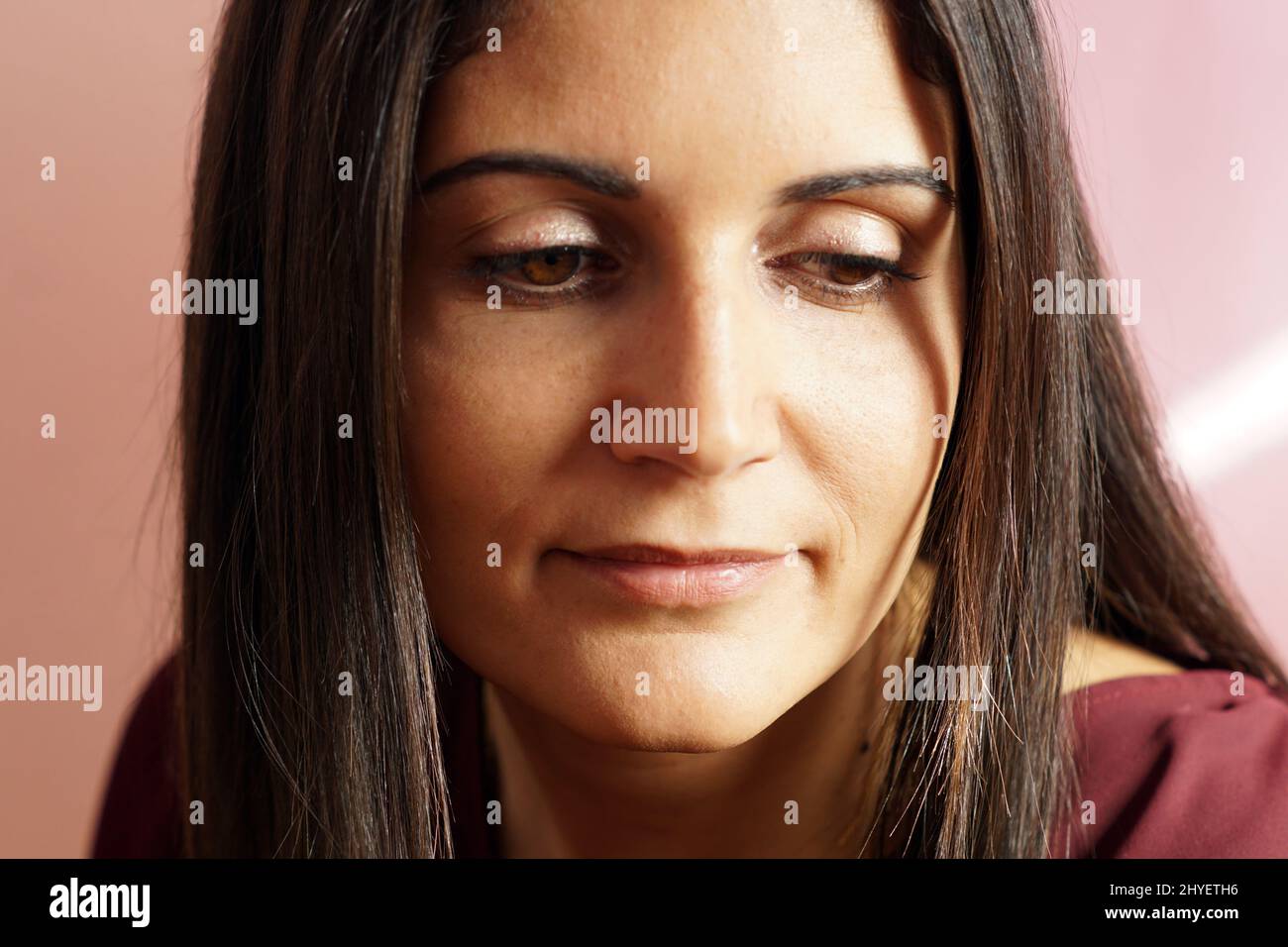 Portrait of a Hispanic woman in a burgundy dress looking down Stock Photo -  Alamy