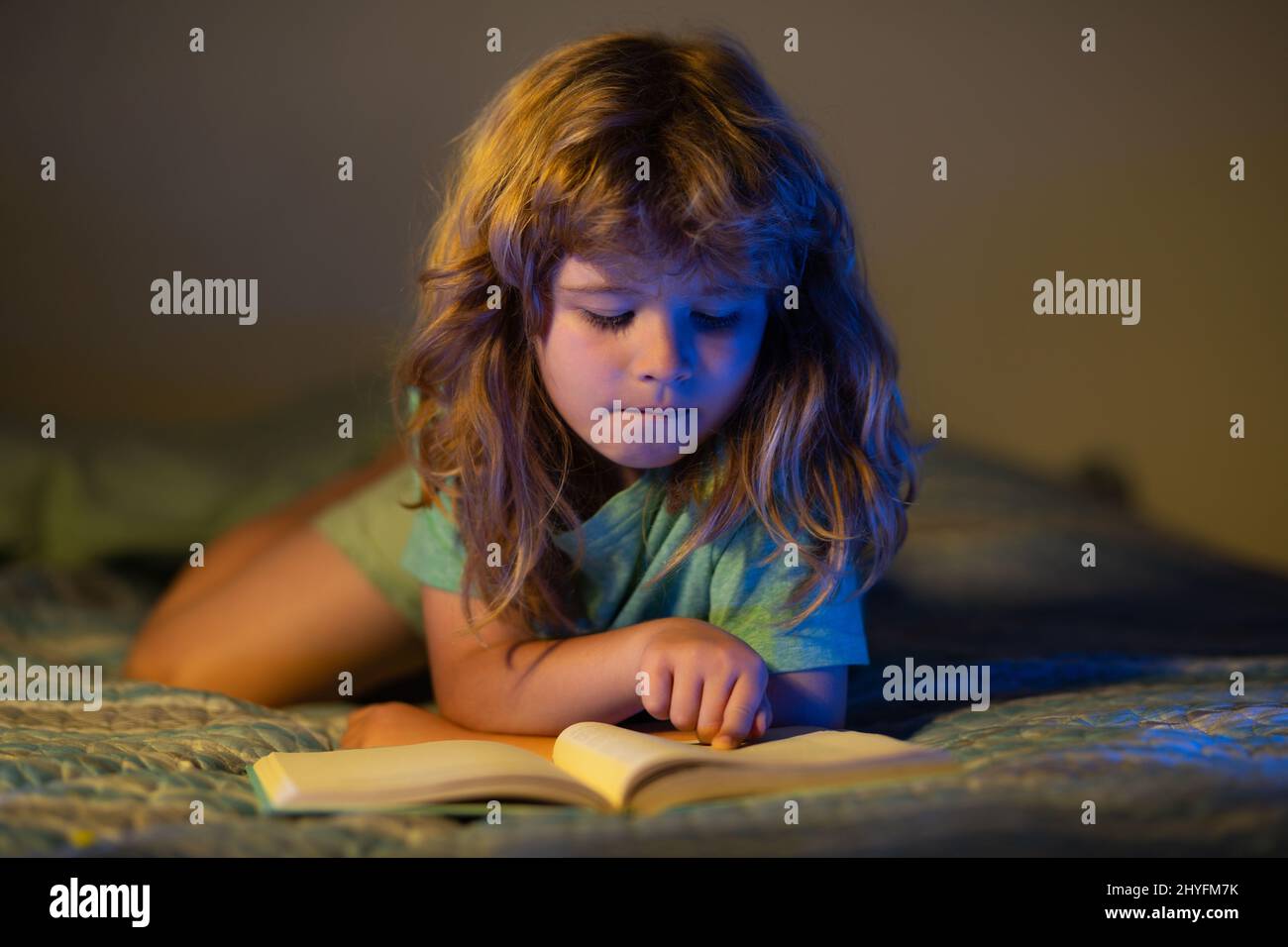 Child reading a book in the dark home. Little boy sitting on in living ...