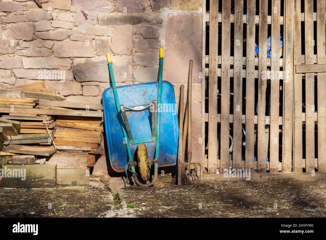 Blue wheelbarrow next to a storage shed in a countryside Stock Photo