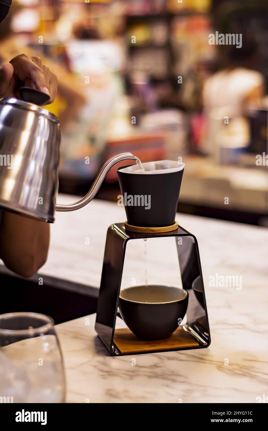 Shallow focus of a metal jug pouring a hot coffee on a Drip coffee